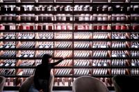 a woman points at a wall of wine bottles at Elexus Apartments Poiana Brasov in Poiana Brasov