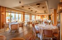 a restaurant with white tables and chairs and windows at Roslin Beach Hotel in Southend-on-Sea
