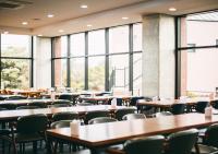 an empty cafeteria with tables and chairs and windows at Hotel Sweet Castle Jeju Hamdeok in Jeju