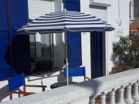 a blue and white umbrella and two chairs on a porch at L Imperatrice in Berck-sur-Mer