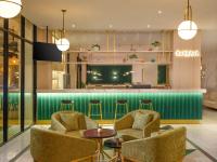 a lobby with chairs and a bar in the background at Elsotel Purwokerto By Daphna Management in Purwokerto