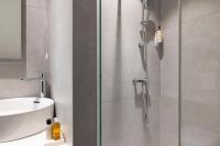 a glass shower in a bathroom with a sink at Hôtel Du Dragon in Strasbourg
