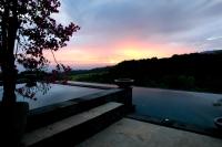 a swimming pool with a sunset in the background at Rinjani Lodge in Senaru