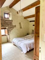 a bedroom with a bed in a stone wall at Bedousses in Aujac