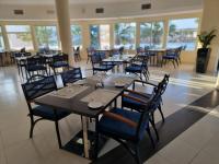 uma sala de jantar com mesas, cadeiras e janelas em Holiday Beach Resort em Dibba
