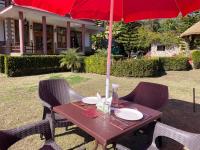 a picnic table with a red umbrella and chairs at Sangita Resorts in Nainital