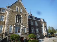 an old brick building with flowers in front of it at Le Château de Rendeux in Rendeux