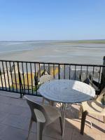 a table and chairs on a balcony with the beach at La Vieille Auberge in Le Mont Saint Michel