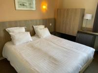 a bed with white sheets and pillows in a room at La Vieille Auberge in Le Mont Saint Michel