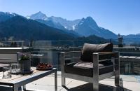 a chair on a balcony with a view of mountains at Apartment BergArt in Garmisch-Partenkirchen