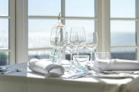 Una mesa con copas de vino y cubiertos encima. en Hjerting Badehotel, en Esbjerg