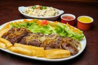 a plate of food with meat and salad and rice at Carnaubinha Praia Resort in Luis Correia