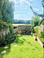 Un patio trasero con un jardín con césped verde y una cerca. en Eco lodge in tranquil setting close to Central London, en Londres