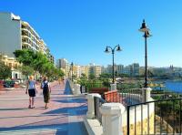 two women walking down a sidewalk near the water at Modern 2 Bedroom Maisonette in Central Sliema in Sliema