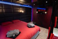 a bedroom with a red bed and a neon sign at Capsule Secret - Jacuzzi - Netflix &amp; Home cinéma - Jeux de couple - Barre de pole dance in Valenciennes
