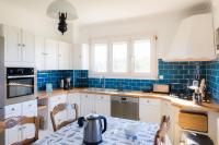 a kitchen with white cabinets and blue tiles at Jolie maison pour 8 personnes in Plobannalec-Lesconil