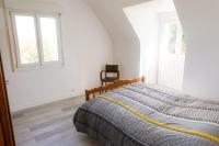 a bed in a white room with two windows at Jolie maison pour 8 personnes in Plobannalec-Lesconil