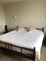 a bed with white sheets and red pillows on it at Residentie Zeezicht in Eksel