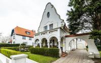 una casa blanca con un arco en el patio en B&amp;B Maison Rabelais, en De Haan