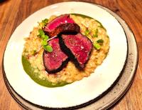 a plate of food with meat on top of risotto at Seehotel Hartung & Ferienappartements in Füssen
