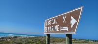 un cartel en la playa con el océano en el fondo en Chateau de Marine Boutique Hotel, en Struisbaai