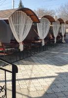 een rij stoelen met witte gordijnen op een terras bij Hotel Konus in Făleşti