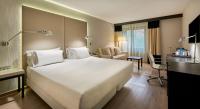 a bedroom with a large white bed and a living room at NH Lleida Pirineos in Lleida