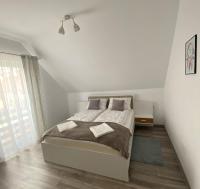 a white bedroom with a bed and a window at FENYŐ APARTMAN House I in Odorheiu Secuiesc