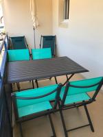 a wooden table and two blue chairs in a room at APPARTEMENT VUE OCEAN ET PISCINE in Lacanau