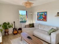 sala de estar con sofá y guitarra en Superbe appartement, grande terrasse vue mer et montagne, en San Juan de Luz