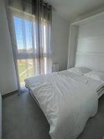 a white bed in a bedroom with a large window at Les Pieds dans le Sable in Le Grau-du-Roi