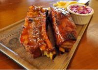 two pieces of ribs on a cutting board with sauce at Hotel Boutique Victoria in Moyogalpa