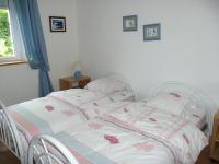 a bedroom with a white bed with pink flowers on it at Granite stone house with fireplace, Plouguerneau in Plouguerneau