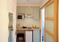 a small kitchen with white cabinets and a sink at Hotel et Studios Le Marina Baie de La Baule in Pornichet