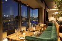 un restaurante con mesas, sofás verdes y ventanas en Century City Hotel Bridgewater, en Ciudad del Cabo