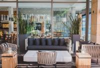 una sala de estar con sofá, mesas y sillas en Century City Hotel Urban Square, en Ciudad del Cabo