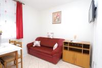 a living room with a red couch and a table at Apartments Lias - with restaurant in Rogoznica