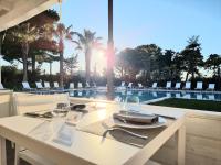 een witte eettafel met uitzicht op een zwembad bij San Lorenzo Boutique Hotel & SPA in Polignano a Mare
