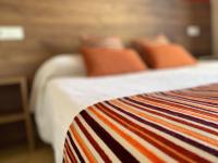 a close up of a bed with orange pillows at Hôtel Le Belvedere in Saint-Cyprien