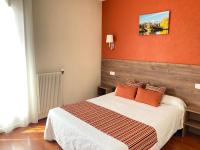 a bedroom with a bed with an orange wall at Hôtel Le Belvedere in Saint-Cyprien