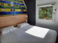 Un dormitorio con una cama blanca y una ventana. en Kyriad Direct Caen Nord Memorial, en Caen