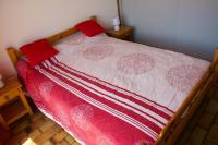 a bed with a pink and white comforter and red pillows at Studio avec vue sur la mer et balcon amenage a Le Barcares in Le Barcarès