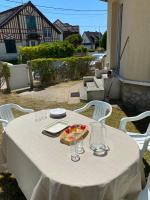 a white table with glasses and a plate of fruit on it at La plage au bout du jardin &#47; Sword Beach cottage in Hermanville-sur-Mer