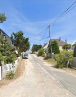 a street with houses and a car on the road at La plage au bout du jardin &#47; Sword Beach cottage in Hermanville-sur-Mer