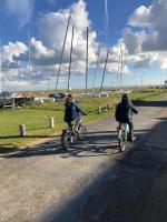 two people riding bikes down a road with sailboats at La plage au bout du jardin &#47; Sword Beach cottage in Hermanville-sur-Mer