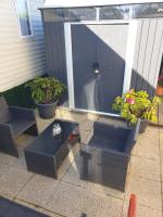 a patio with two chairs and a table and plants at La Chanterie Agréable Mobil-Home Résidentiel Normand in Saint-Pair-sur-Mer