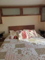 a bed with pillows and a quilt on it at La Chanterie Agréable Mobil-Home Résidentiel Normand in Saint-Pair-sur-Mer