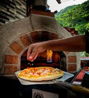 a person is putting a pizza into an oven at Tiki Hut Hostel in Palomino