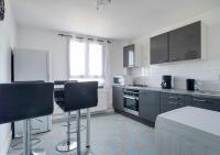 a kitchen with gray cabinets and black chairs at Le PRIVILEGE aux PORTES de PARIS in Bagnolet