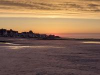 a view of the beach at sunset at Hotel de Normandie in Saint-Aubin-sur-Mer